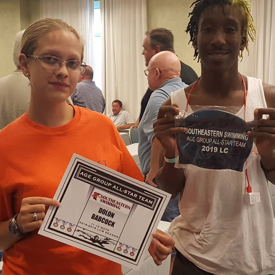 Two people holding swimming awards together.