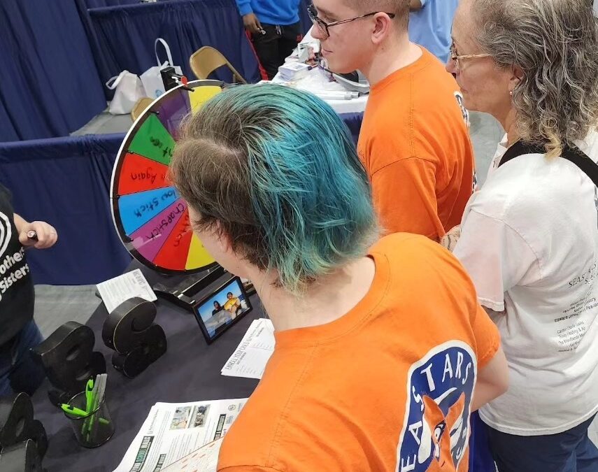 Young people engaging with a colorful spinning wheel at an event booth.