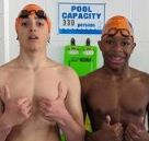 Two swimmers giving thumbs up near a pool capacity sign.