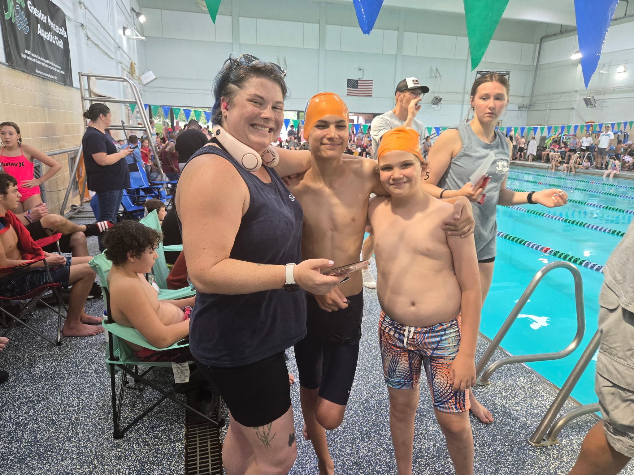 Four swimmers posing by the pool, smiling and showing camaraderie.
